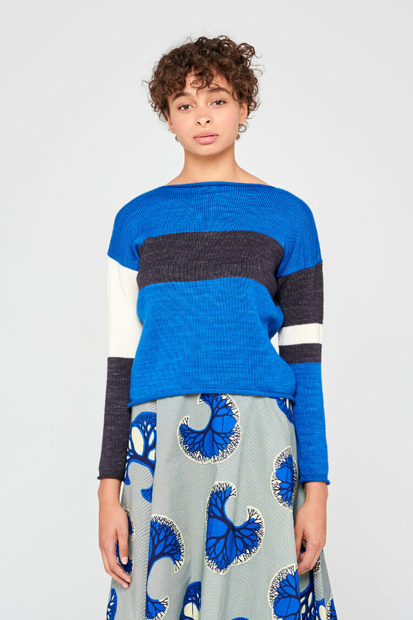 Femme portant un pull en laine merinos extrafine bleu vif, couleur intense et  rayures asymétriques.