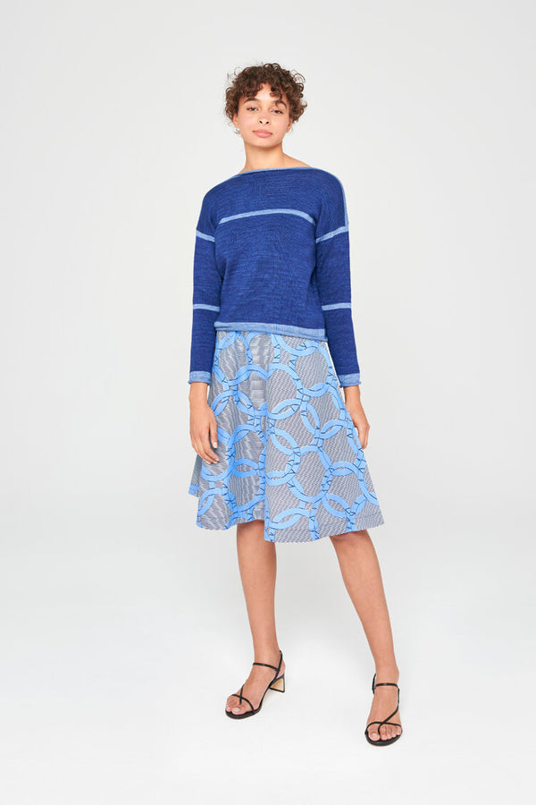 Femme portant un pull en laine merinos extrafine bleu orage, portée avec une jupe midi.